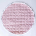 Tapis d'éveil rond rose à matelassage carré et bord pompons.
