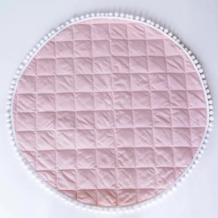 Tapis d'éveil rond rose à matelassage carré et bord pompons.