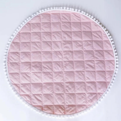 Tapis d'éveil rond rose à matelassage carré et bord pompons.